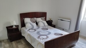 Een slaapkamer met een houten bed, een nachtkastje met een lamp en een wandairconditioner.