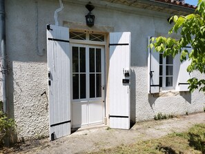 A white building with a large open door and a window with shutters. - Bienvenue en sud Gironde (Villandraut)