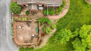An aerial view of a property with a brick patio, outdoor seating, and a swimming pool.