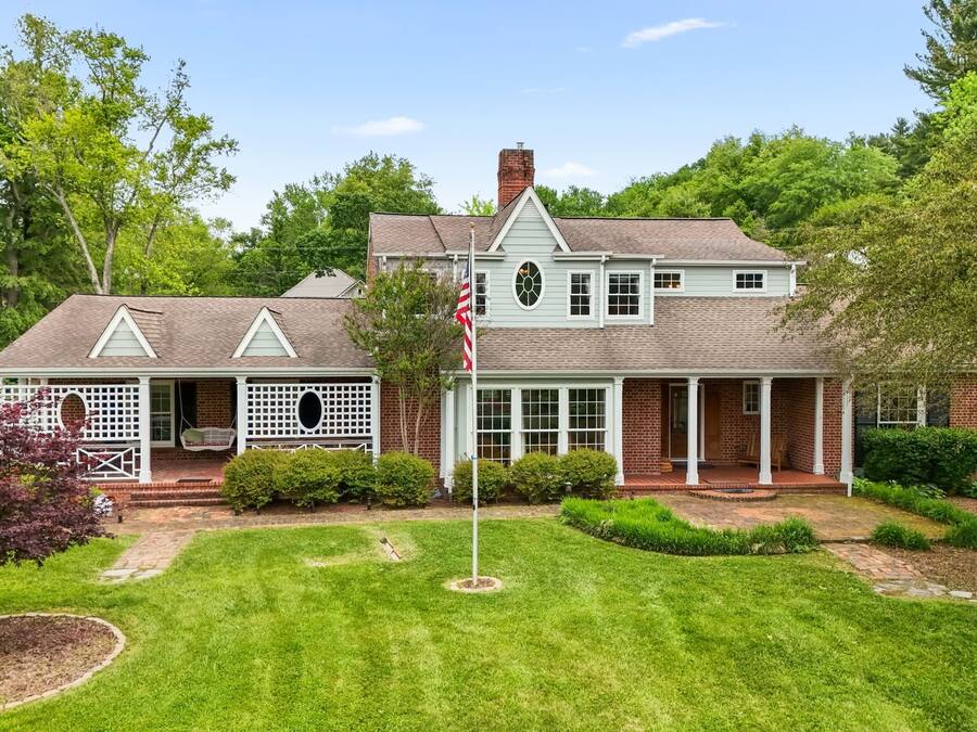 A two-story house with a brick exterior, a front porch, and a well-maintained lawn.