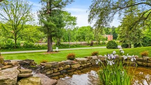 Ein angelegter Garten mit Teich, Steinmauern und verschiedenen Bäumen und Sträuchern.