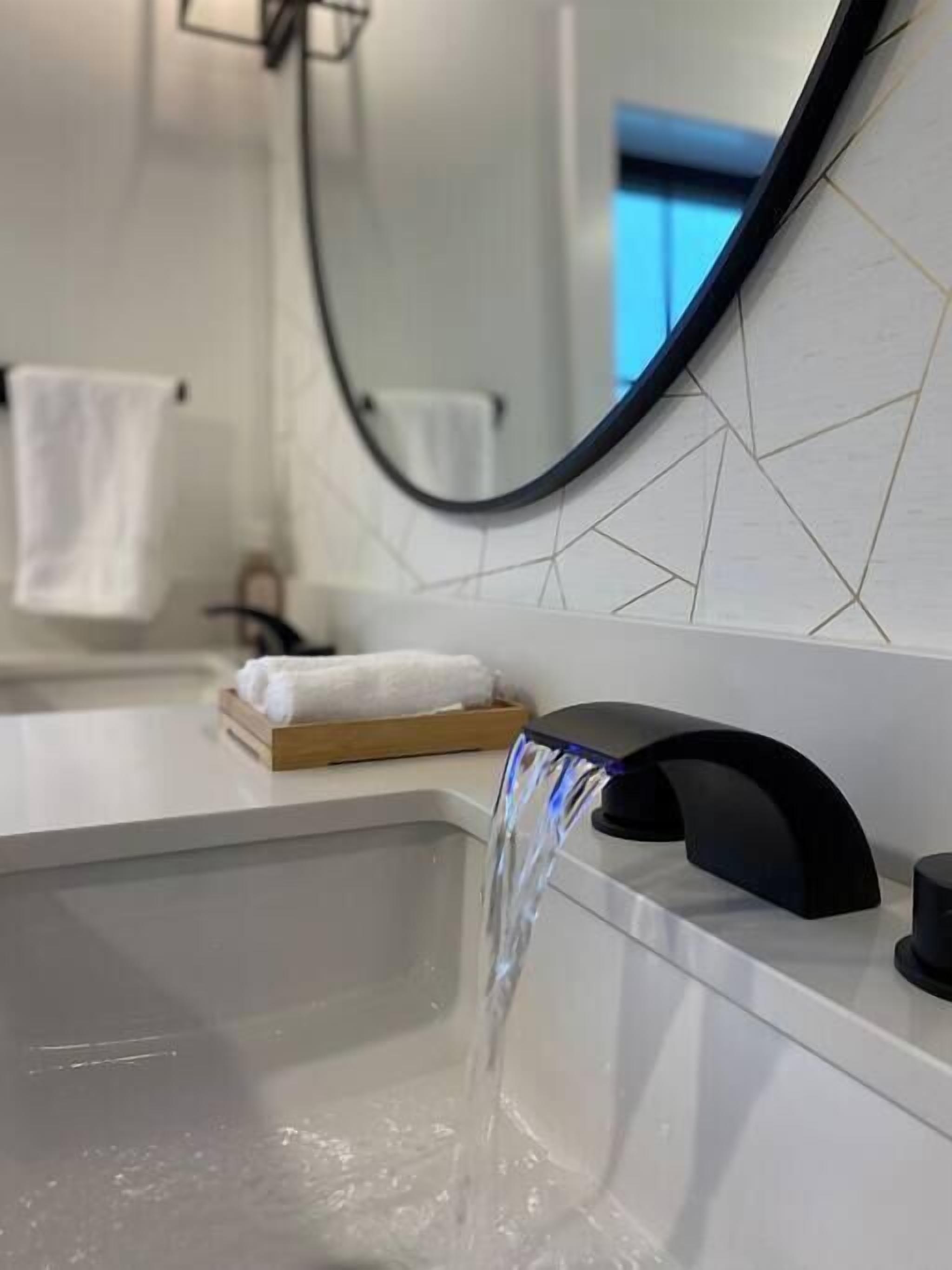 Une salle de bain moderne avec un lavabo rectangulaire, un robinet noir et un miroir à cadre noir.