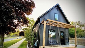 Une maison moderne avec un porche en bois, un petit jardin et un ciel dégagé.