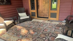 A porch with wicker chairs, a patterned rug, and a wooden door. - Centrally located one bedroom + Office (Calgary)