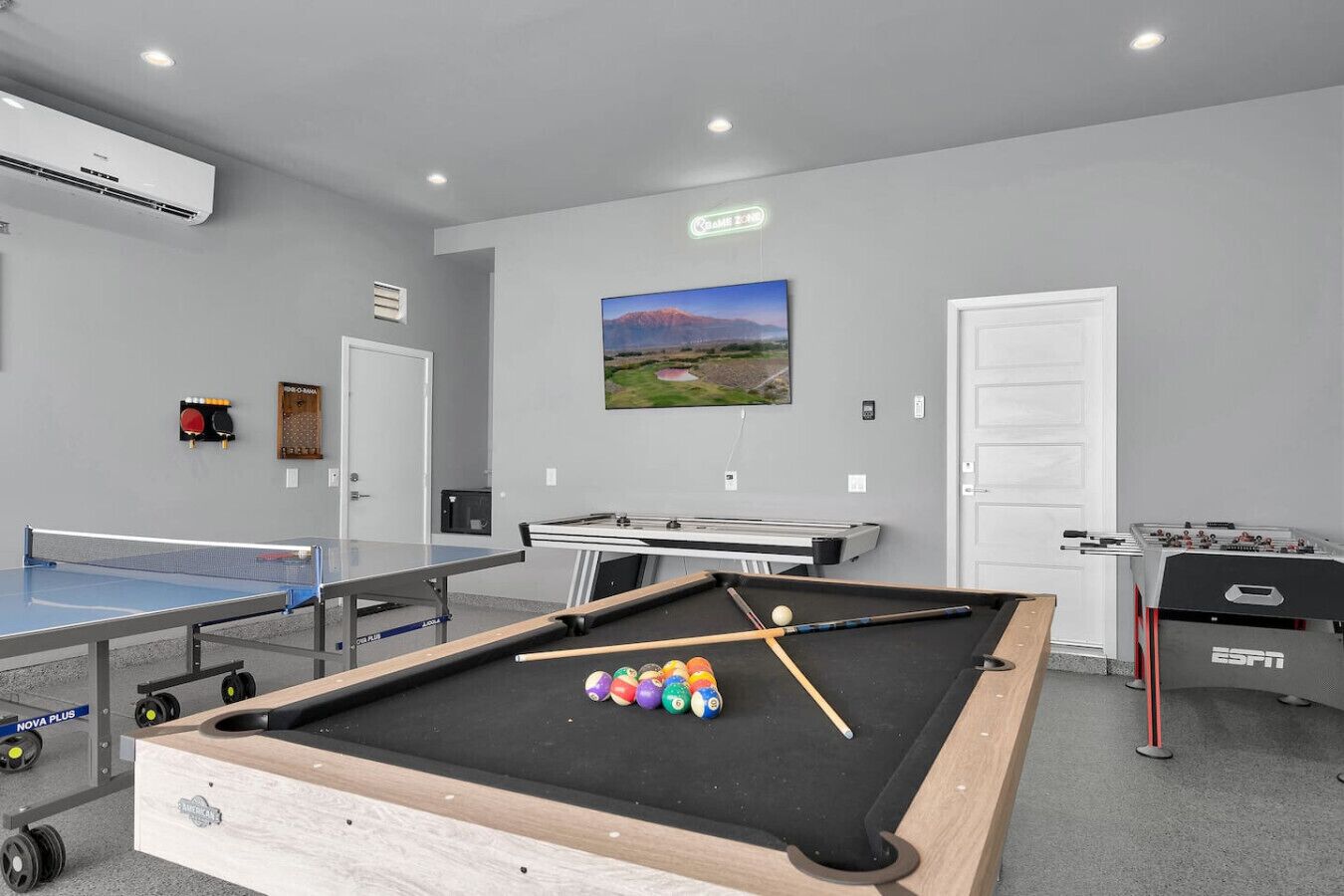 A recreational room with a pool table, foosball table, ping pong table, and billiards equipment.