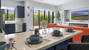 A modern kitchen with a central island, dark cabinets, and a large window offering a view of greenery. - New+Modern/Pool/Spa/Gameroom/Poker/Massage chair (Indio)