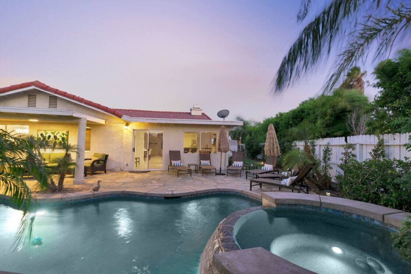 Una casa con piscina, mobiliario exterior y zona de patio.