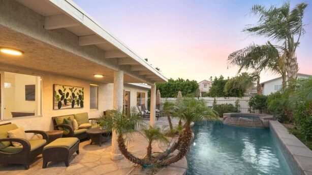 A pool area with lounge chairs and a small waterfall feature. - Best value,location, gameroom, pool+good size yard (Bermuda Dunes)