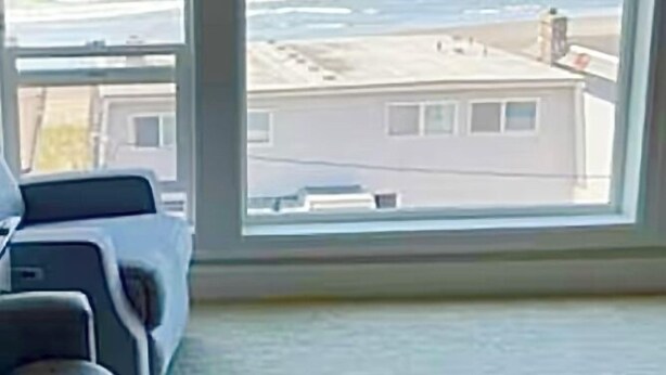 Una habitación con un ventanal grande que da a una playa y el océano.