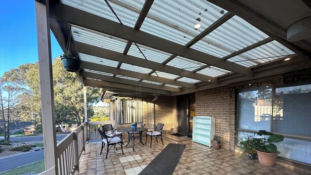 A covered patio with a table and chairs, a potted plant, and a view of the street. - Hill top view house, high speed wifi, Netflix & Prime Video (Sunbury)