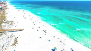 Una playa con un paseo marítimo de madera y gente paseando.