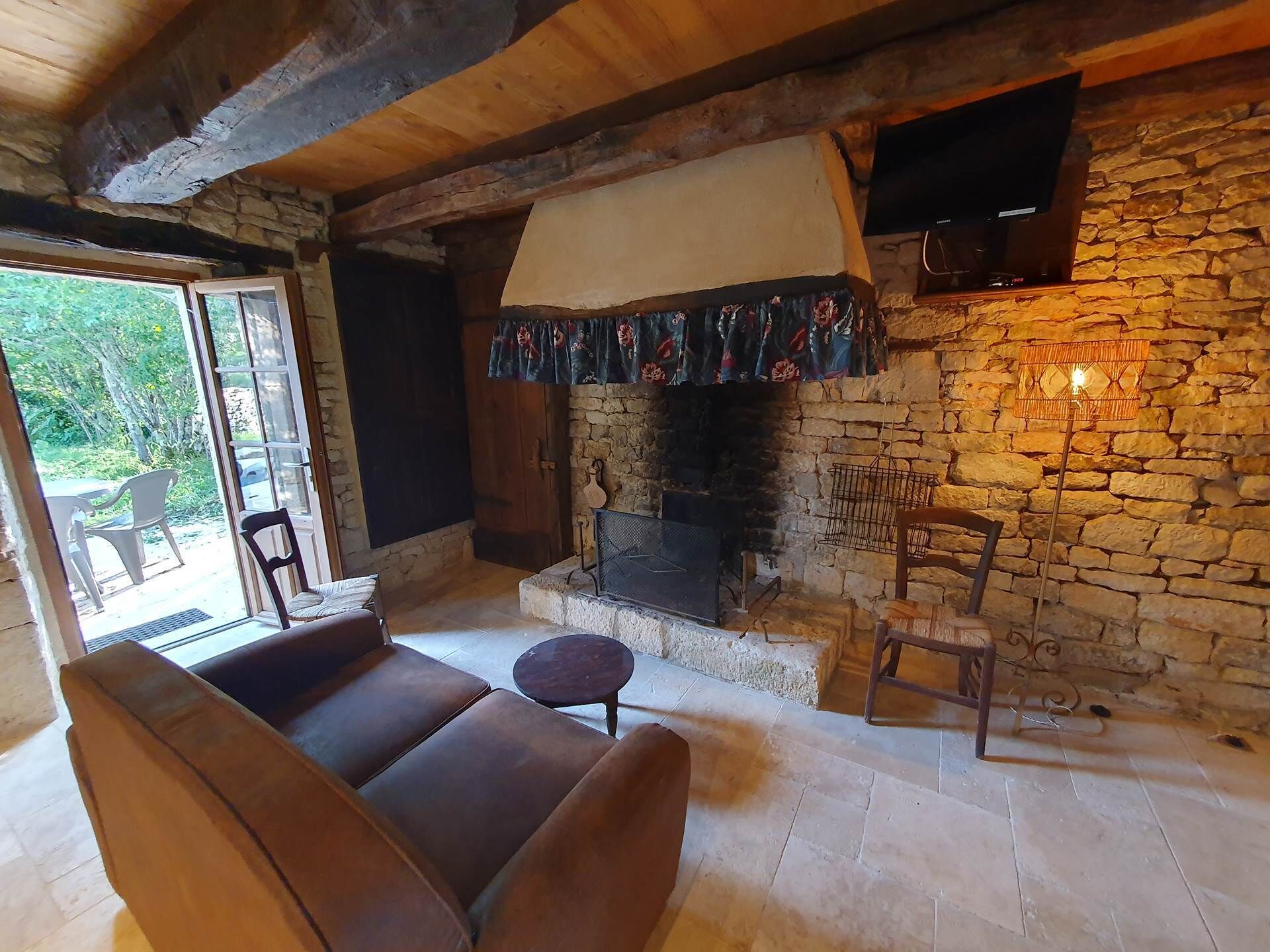 A cozy living room with a stone fireplace, wooden beams, and a comfortable seating area.