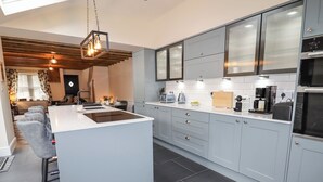 A modern kitchen with grey cabinets, a central island, and a dining area with a sofa and table. - Glan William (Dolwyddelan)