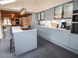 A modern kitchen with grey cabinets, a central island, and a dining area with a sofa and table.