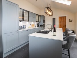 A modern kitchen with grey cabinets, a central island, and a wine bottle.