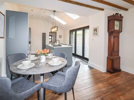 A dining area with a round table, grey upholstered chairs, and a chandelier.