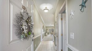 Um corredor com uma guirlanda decorativa na porta à esquerda, uma luminária no teto e enfeites de estrela-do-mar nas paredes.