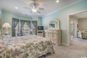 Un dormitorio con cama, cómoda, tocador y ventilador de techo.