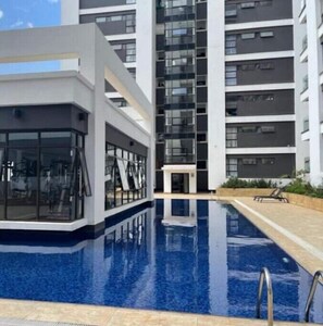 A modern building with a swimming pool, large windows, and a clear sky.