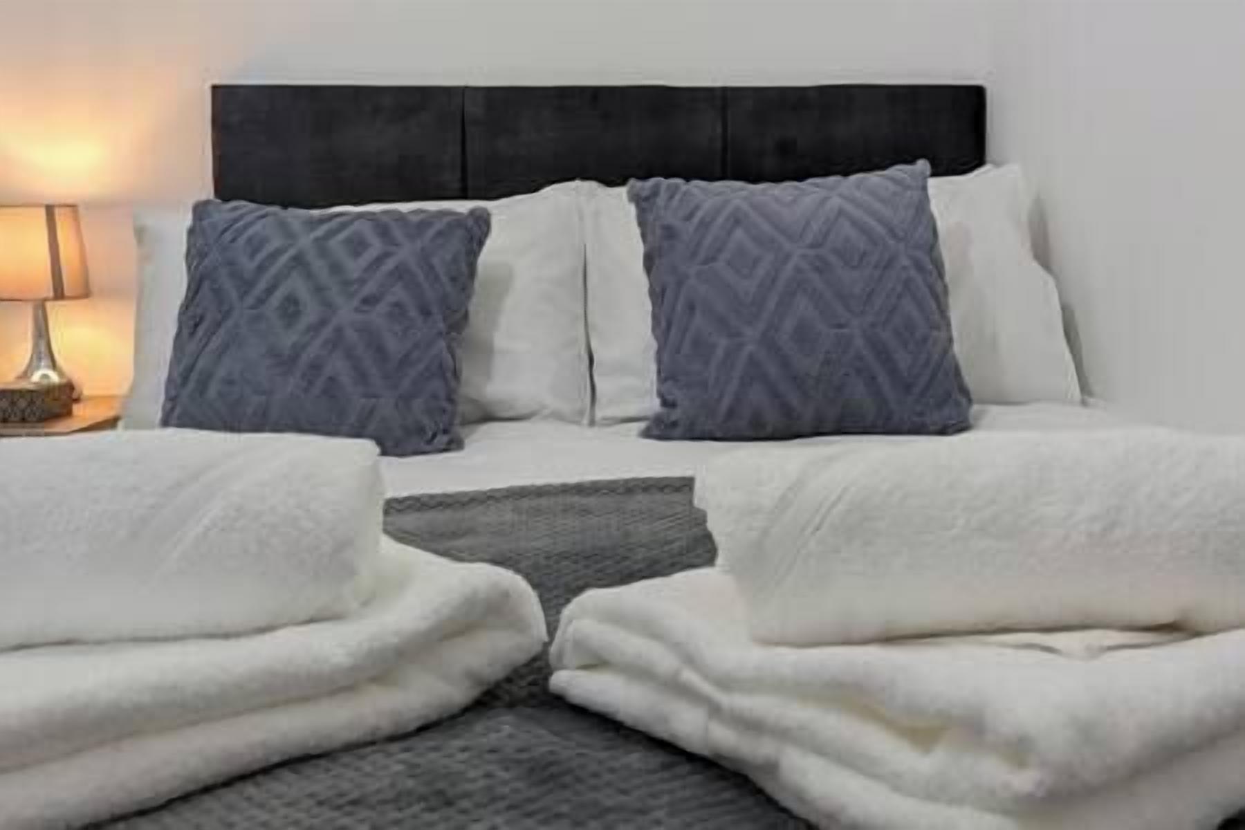 A double bed with a black headboard, two pillows, and a bedside table with a lamp.