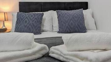 A double bed with a black headboard, two pillows, and a bedside table with a lamp.