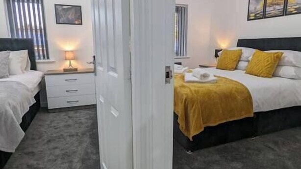 Una camera d'albergo con due letti, un comodino con una lampada e una finestra con persiane.