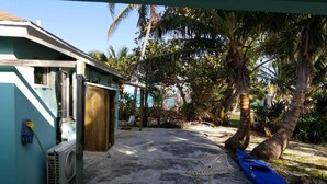 A covered outdoor area with a concrete floor, a blue kayak, and a wooden door.