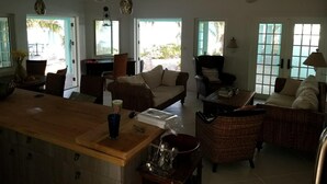 A spacious living area with wicker furniture, a wooden bar, and ceiling fans.