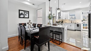 A modern kitchen with white cabinets, a central island, and pendant lighting.