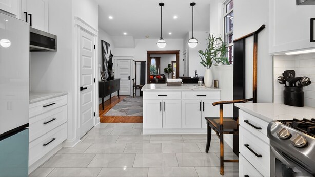 A modern kitchen with white cabinetry, a central island, a stove, and pendant lighting.