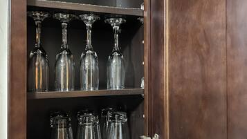 Un mueble de madera con estantes que contienen copas y botellas de vidrio.
