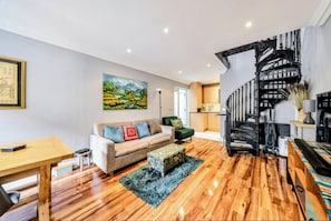 Una sala de estar con sofá, reposapiés y una escalera.
