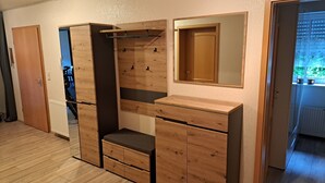 A compact room with a built-in wardrobe, a mirror, and a bench.