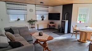 A cozy living room with a sofa, a wooden coffee table with a glass jar, a fireplace, and a TV.