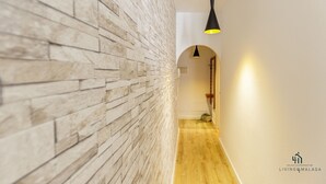 Un couloir avec un mur en pierre et un plancher en bois, qui mène à une porte.