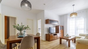 Un salon moderne avec une table à manger en bois, des chaises, un téléviseur et un canapé.
