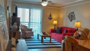 Ein Wohnzimmer mit einem roten Sofa, einem Holzesstisch und einem Deckenventilator.