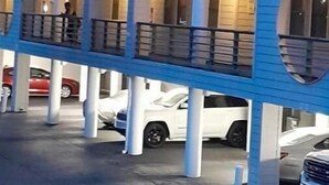 Ein mehrstöckiges Gebäude mit Balkonen und einem darunterliegenden Parkplatz.