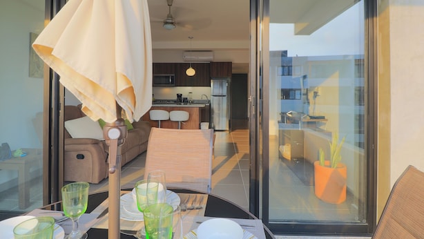 A modern kitchen with a dining area visible through a glass door.