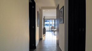 A hallway with a tiled floor, a door on the right, and a framed picture on the left.