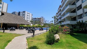 A resort with a pool area, lounge chairs, and a thatched-roof structure.
