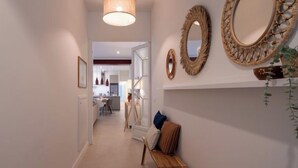 A hallway with a wooden bench, a hanging light fixture, and decorative mirrors on the wall. - Vacation home Rita by Interhome (Malgrat de Mar)