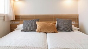 A double bed with a wooden headboard, two bedside lamps, and a window with curtains. - Vacation home Rita by Interhome (Malgrat de Mar)