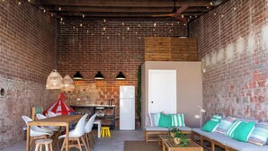 A cozy, rustic dining area with a brick wall, wooden furniture, and string lights. - Vacation home Rita by Interhome (Malgrat de Mar)