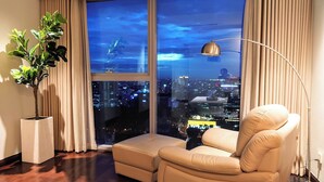 A modern living room with a large window, a sofa, a floor lamp, and a potted plant. - The Rixx Vincom Center (Ho Chi Minh City)