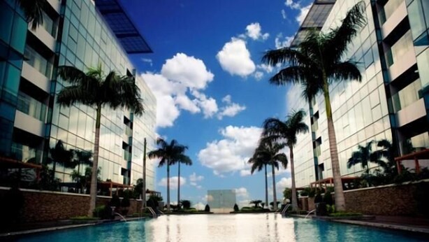 A swimming pool with a clear sky and palm trees, surrounded by modern buildings. - The Rixx Vincom Center (Ho Chi Minh City)