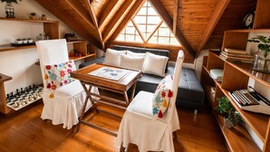 A cozy attic room with wooden beams, a loft bed, a desk, and a chessboard. - HOTEL CASA MADERO (Envigado)