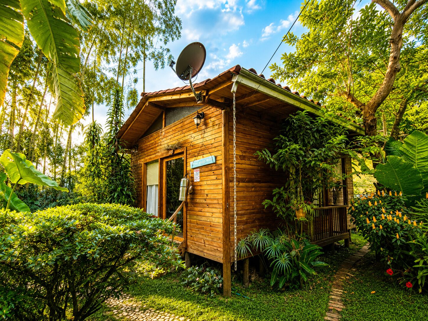 Una cabaña de madera con antena parabólica, rodeada de vegetación exuberante.
