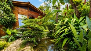 A wooden house with a pond, surrounded by lush greenery. - HOTEL CASA MADERO (Envigado)