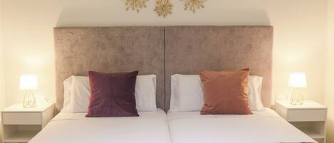 A double bed with two pillows, a striped blanket, and a wall with three decorative gold elements.